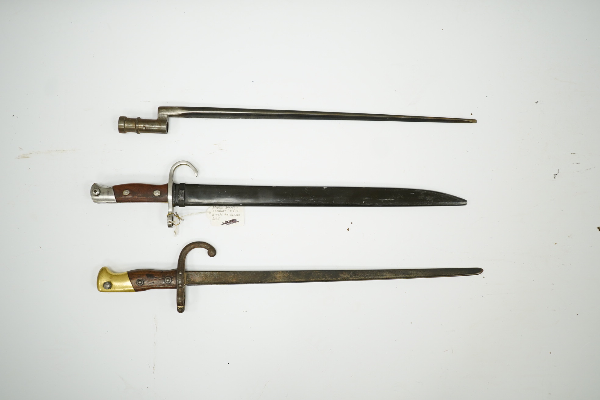 Three bayonets; a Japanese Arisaka bayonet, cleaned bright in its metal scabbard, a Nagant bayonet with quatrefoil blade, in good condition but missing scabbard, and a French Gras bayonet with the blade cut down. Conditi